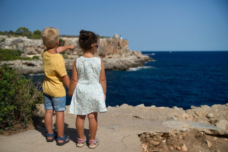 Two children holding hands near a cliff.
